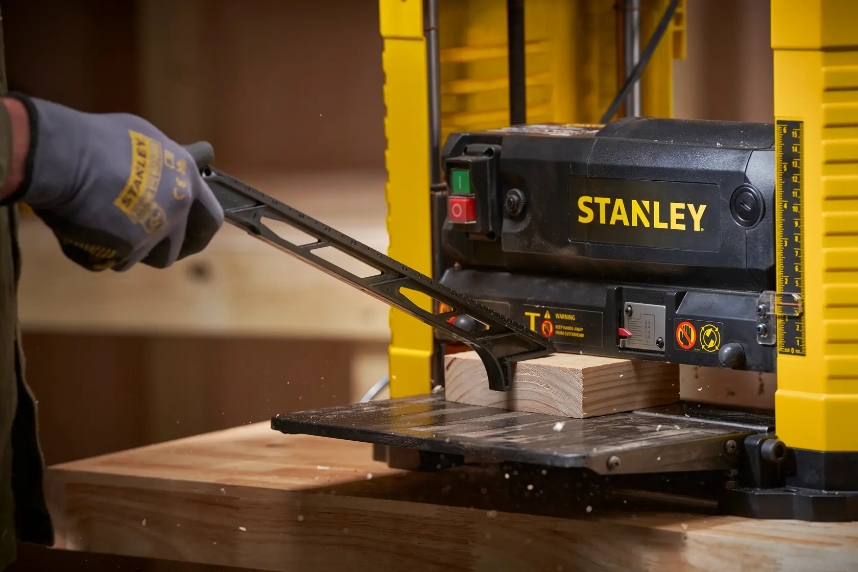 STANLEY STP18-B2 piallatrice da banco in uso, vista ravvicinata di una mano guantata che regola il legno.
