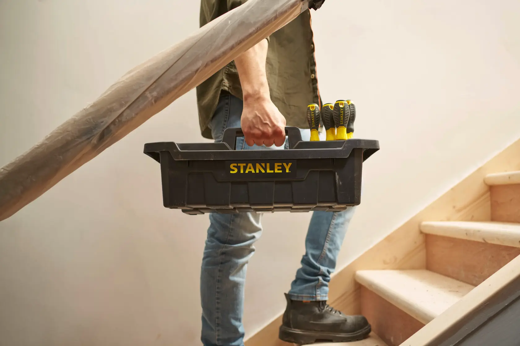 Stanley STST1-72359 cassetta degli attrezzi nera con cacciaviti, trasportata da persona sulle scale.