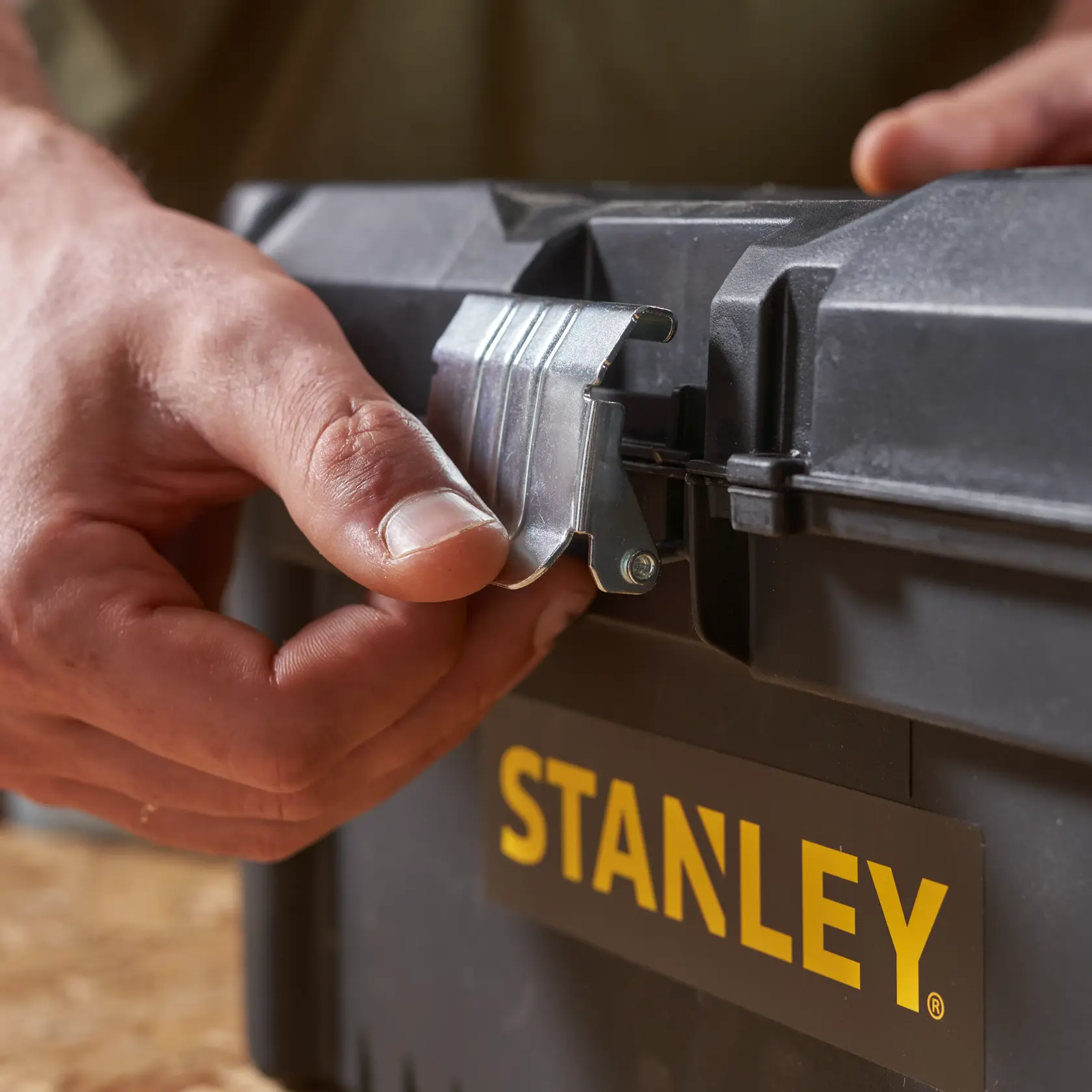 STANLEY STST1-75518-KR cassetta degli attrezzi primo piano, mano apre chiusura metallica, custodia nera, logo giallo.