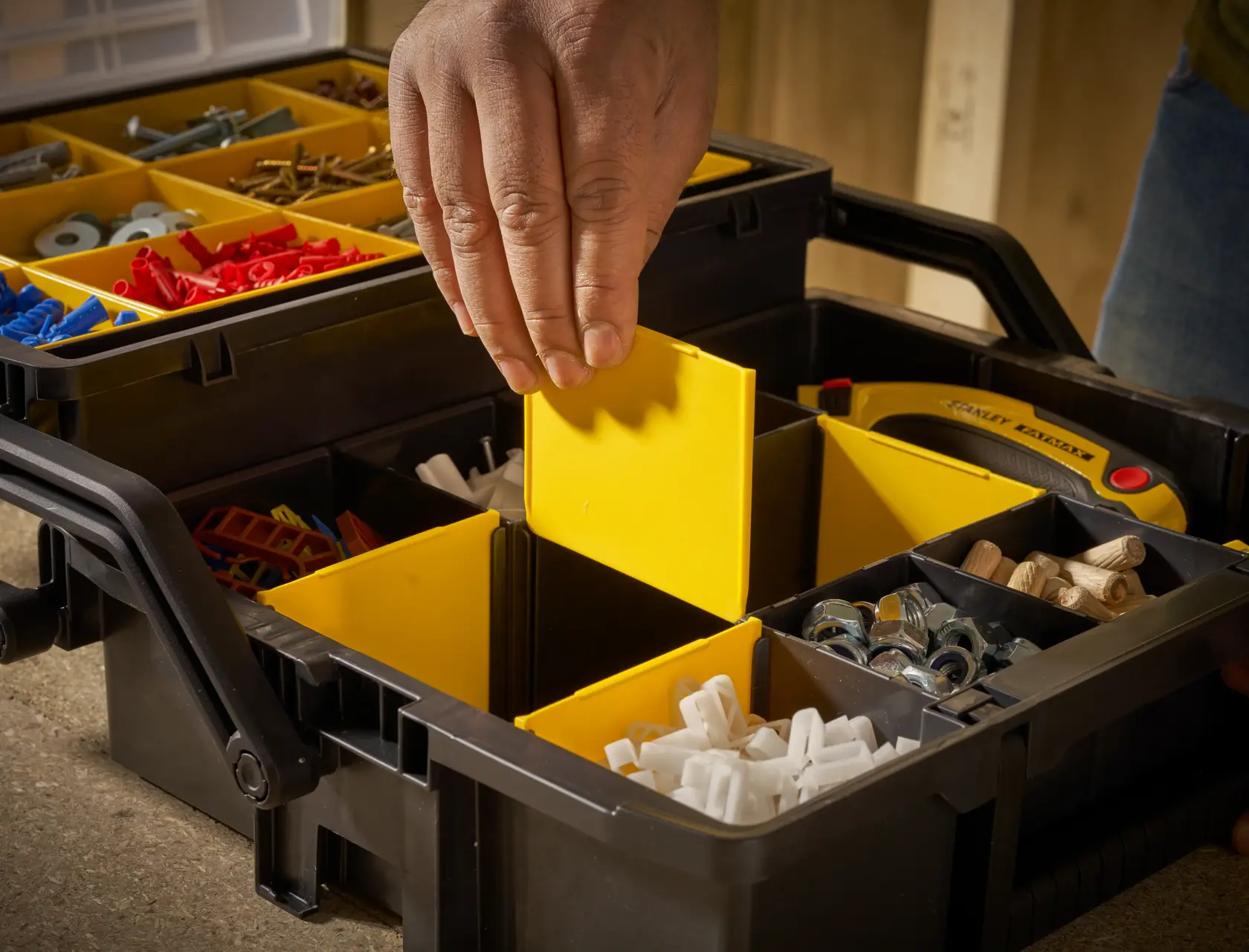 STANLEY STST1-75540 scatola organizer con scomparti gialli, mano che regola il divisore, primo piano.