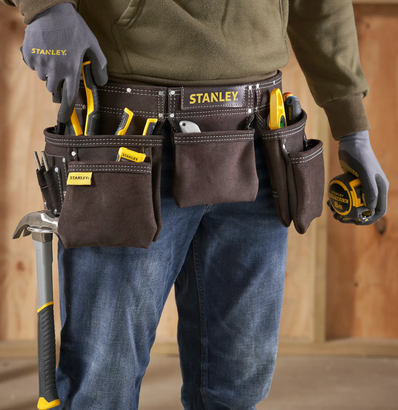 Fotografia della cintura portautensili STANLEY STST1-80113, cintura in camoscio marrone con tasche multiple e utensili indossati.