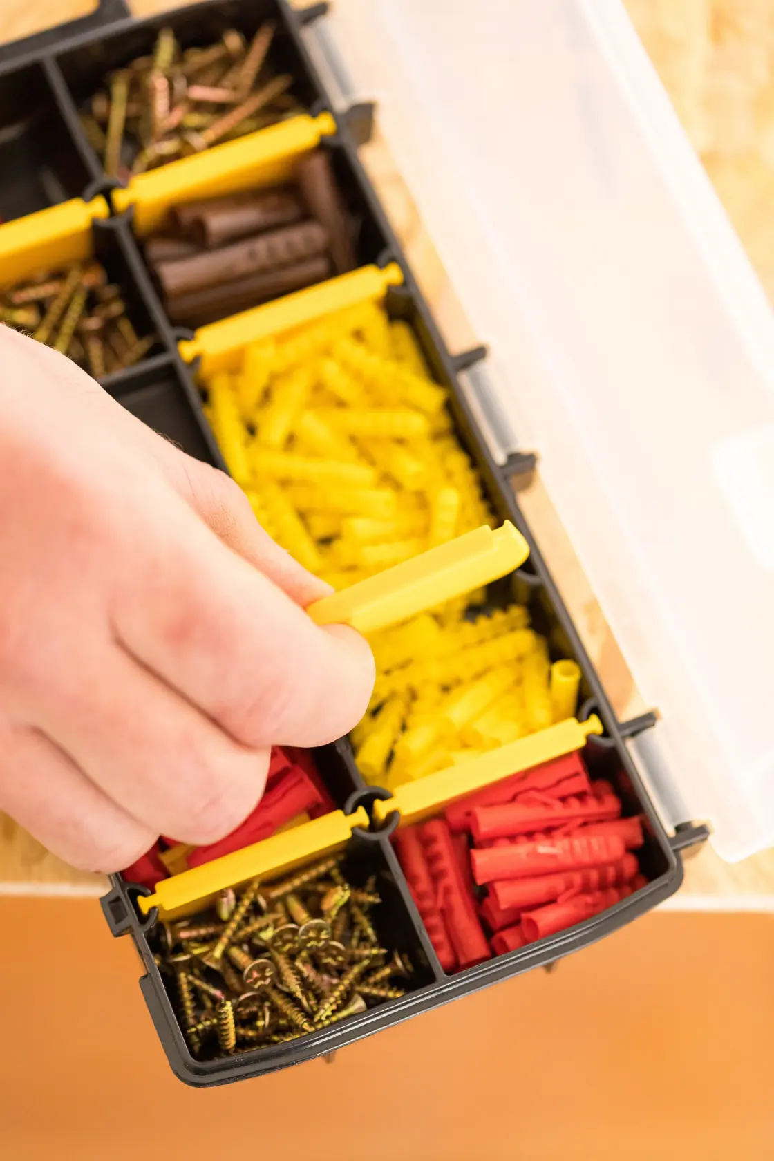 Organizer STANLEY STST81679-1 con viti e tasselli assortiti, mano che apre uno scomparto, vista dall'alto.