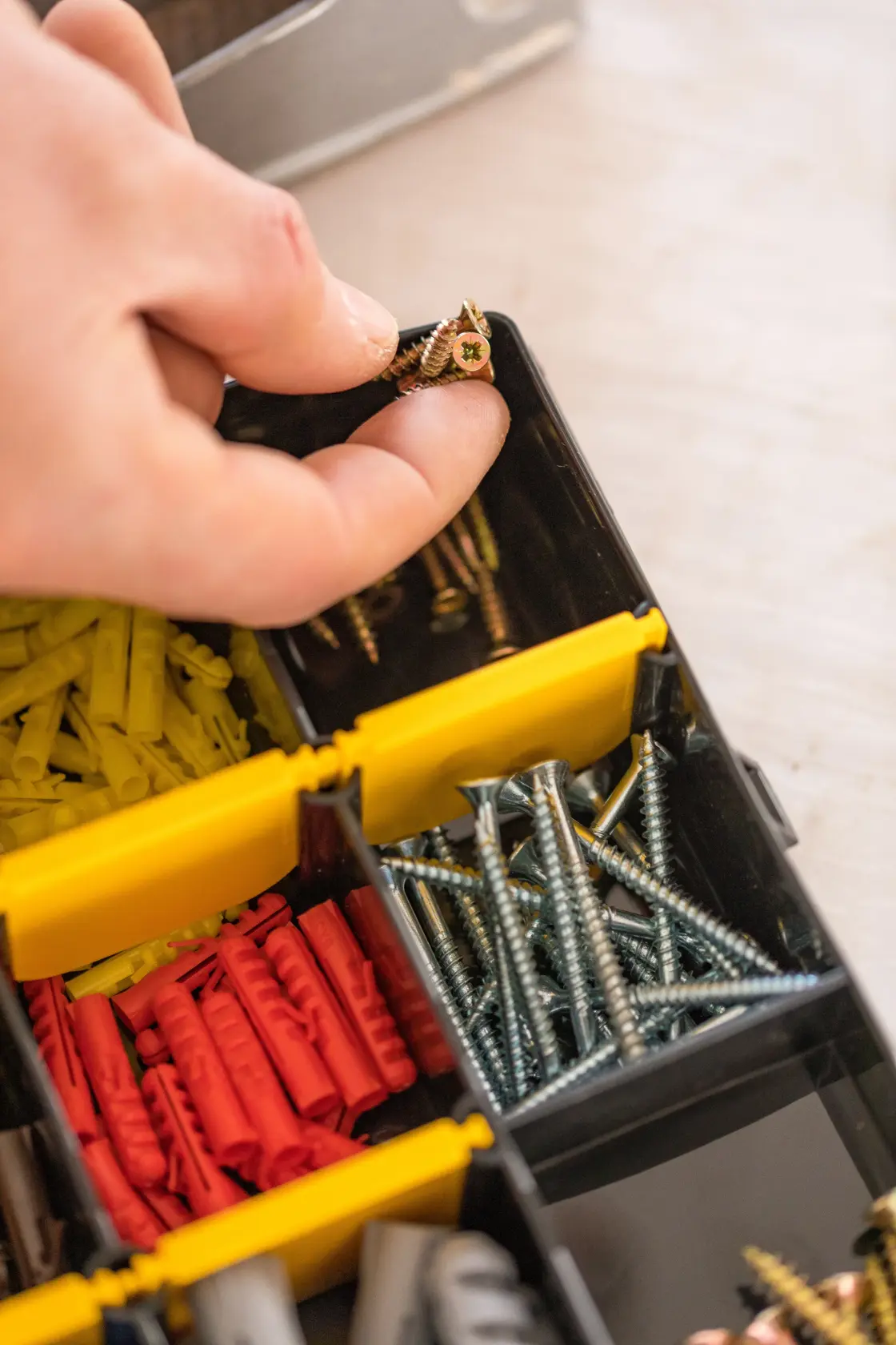 Organizzatore STANLEY STST81681-1 con mano che prende viti, tasselli e fissaggi assortiti visibili.