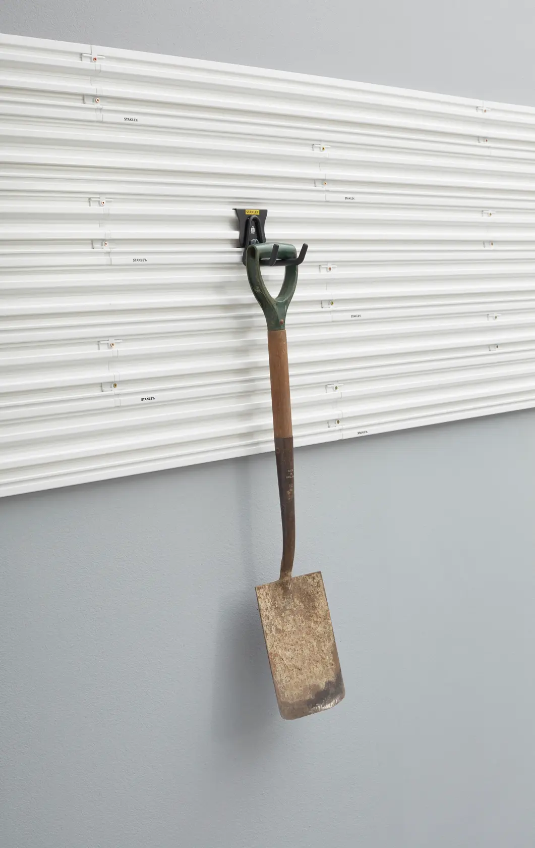 Foto del pannello a parete STANLEY STST82607-1 con pala da giardino in metallo appesa al gancio, vista frontale.