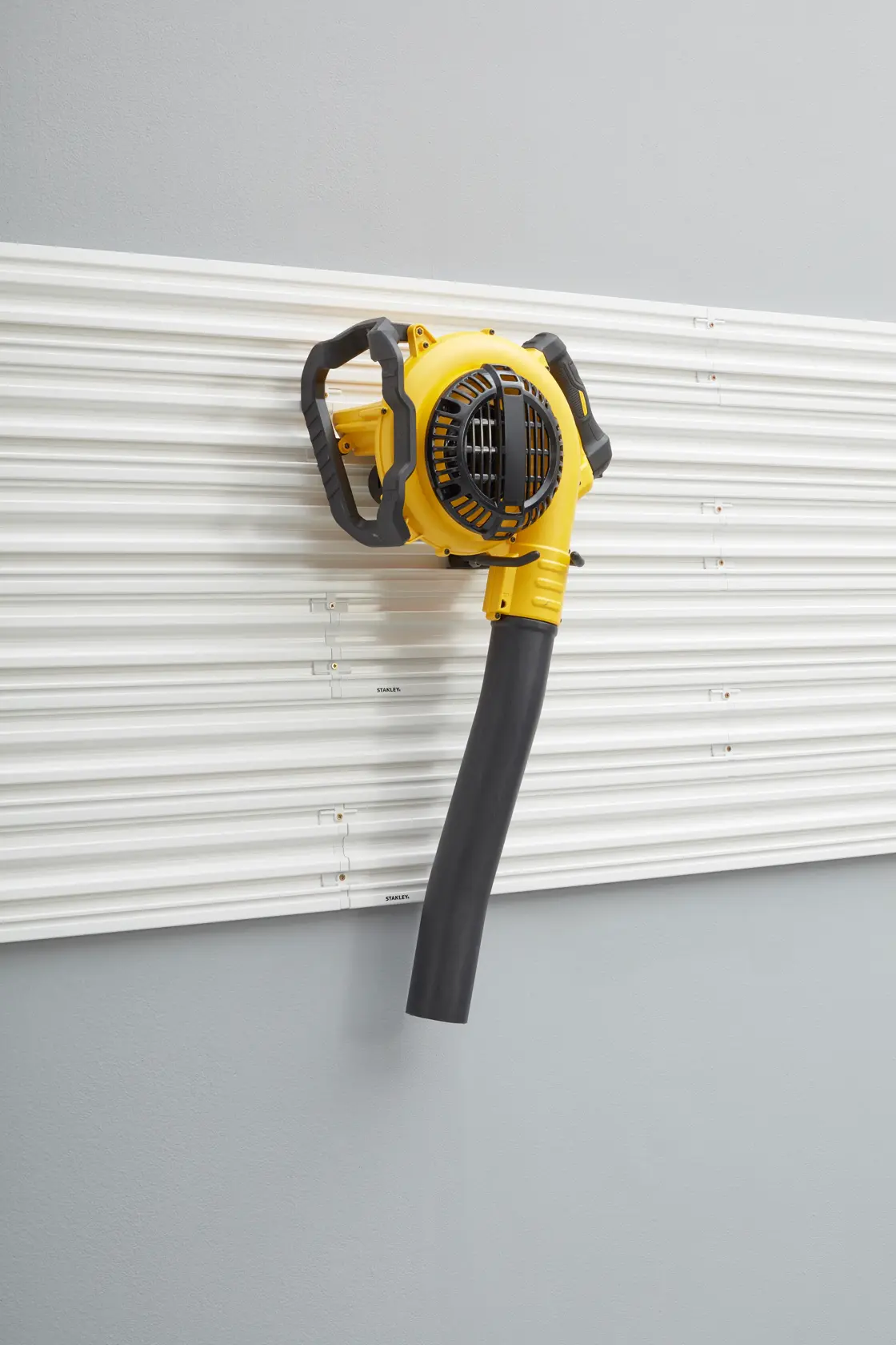 STANLEY STST82609-1 soffiatore giallo montato a parete con ugello nero, angolo frontale, su parete a listelli bianca.