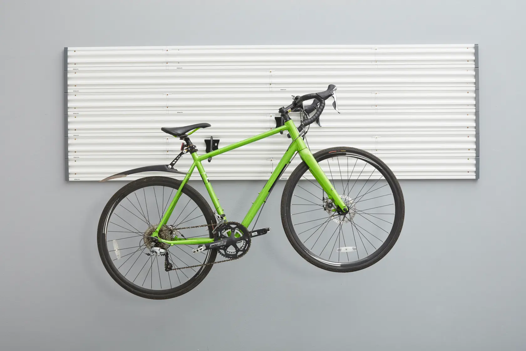 Pannello da parete STANLEY STST82615-1 con bici da strada verde montata su ganci, vista frontale.