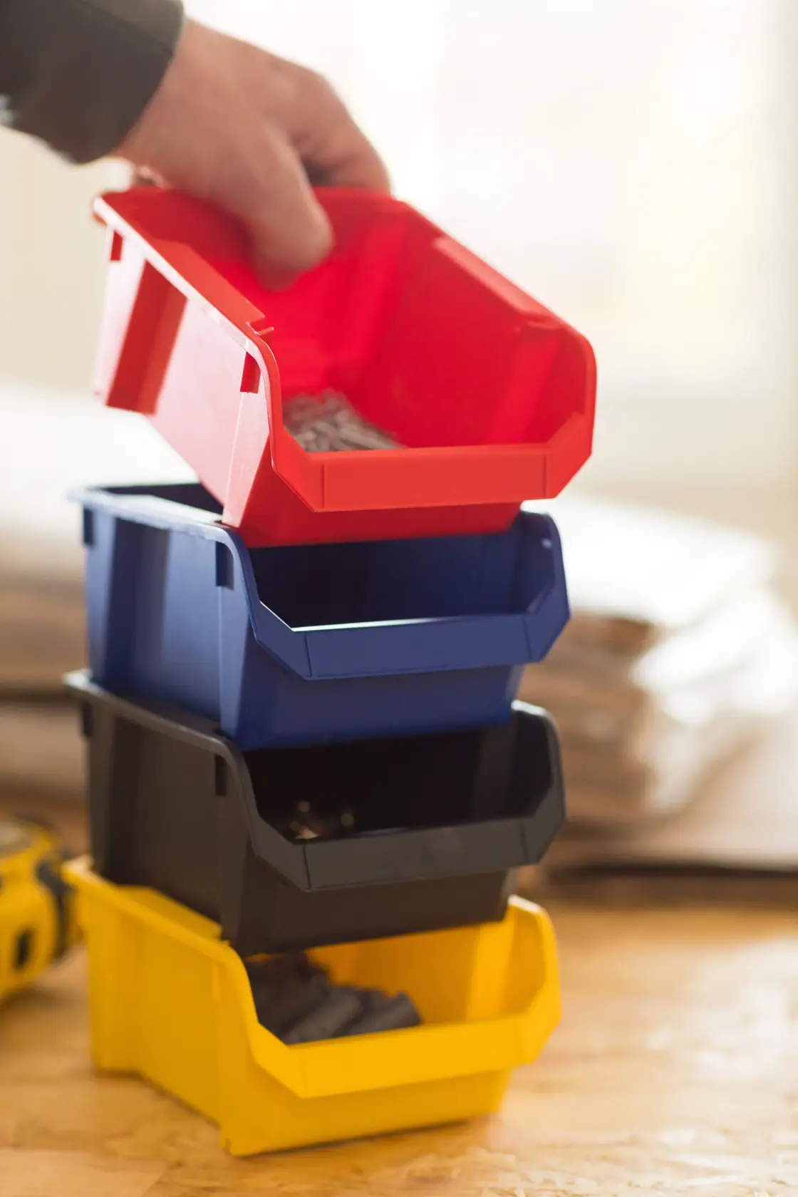 STANLEY STST82736-1 fotografia di una mano che solleva un contenitore rosso da una pila di vaschette di plastica colorate.