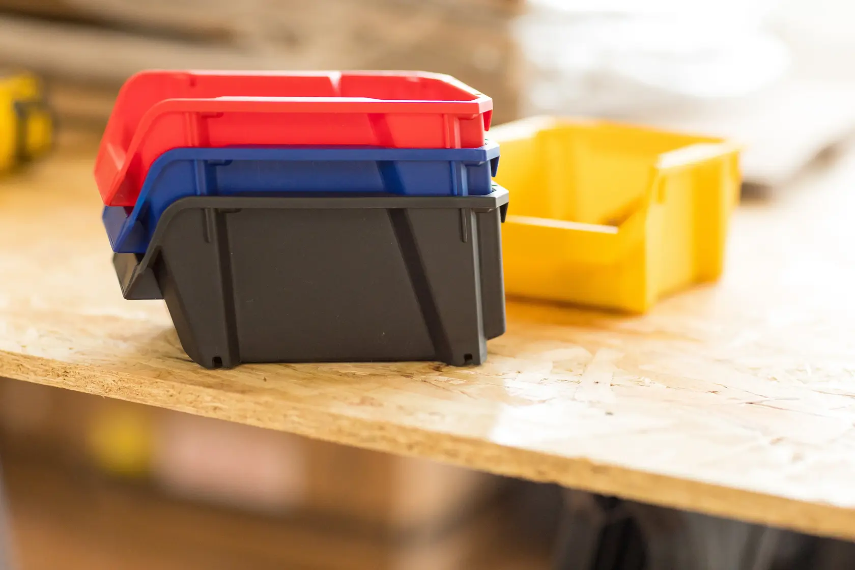 STANLEY STST82736-1 contenitori impilabili in plastica rosso, blu, nero e giallo su superficie in legno.