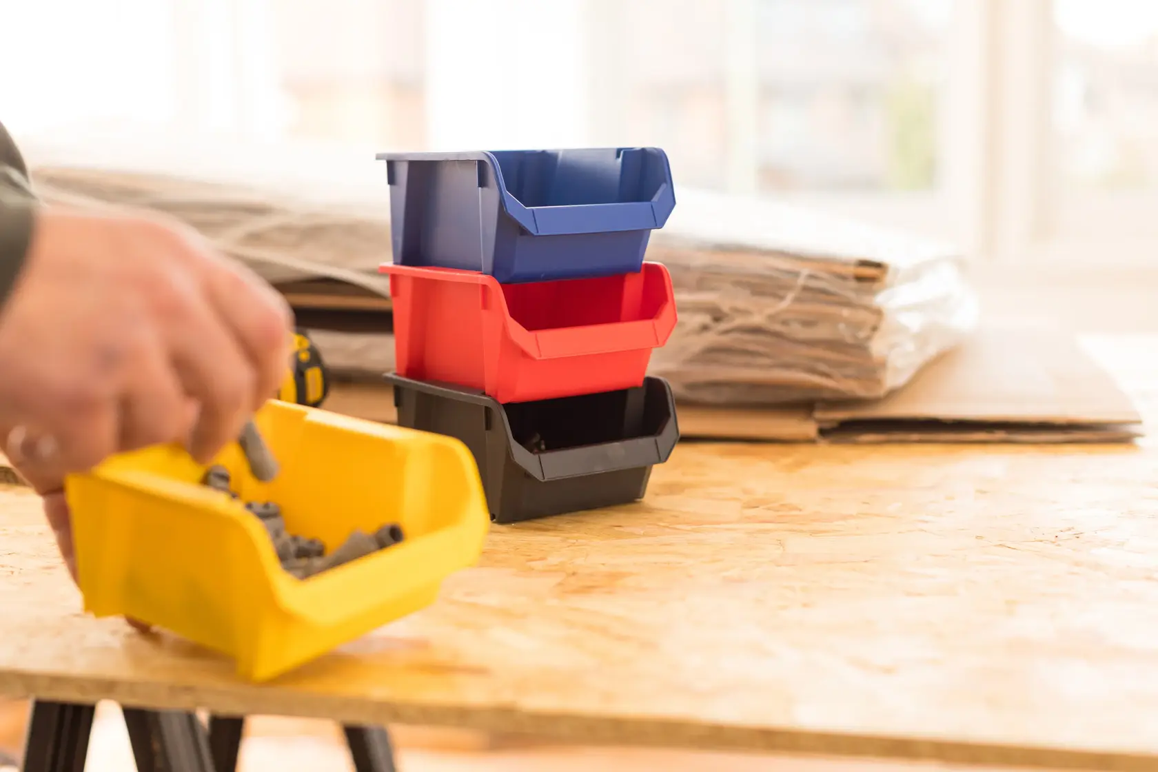 STANLEY STST82737-1 contenitori impilabili in plastica blu, rosso, nero e giallo su un tavolo da lavoro.