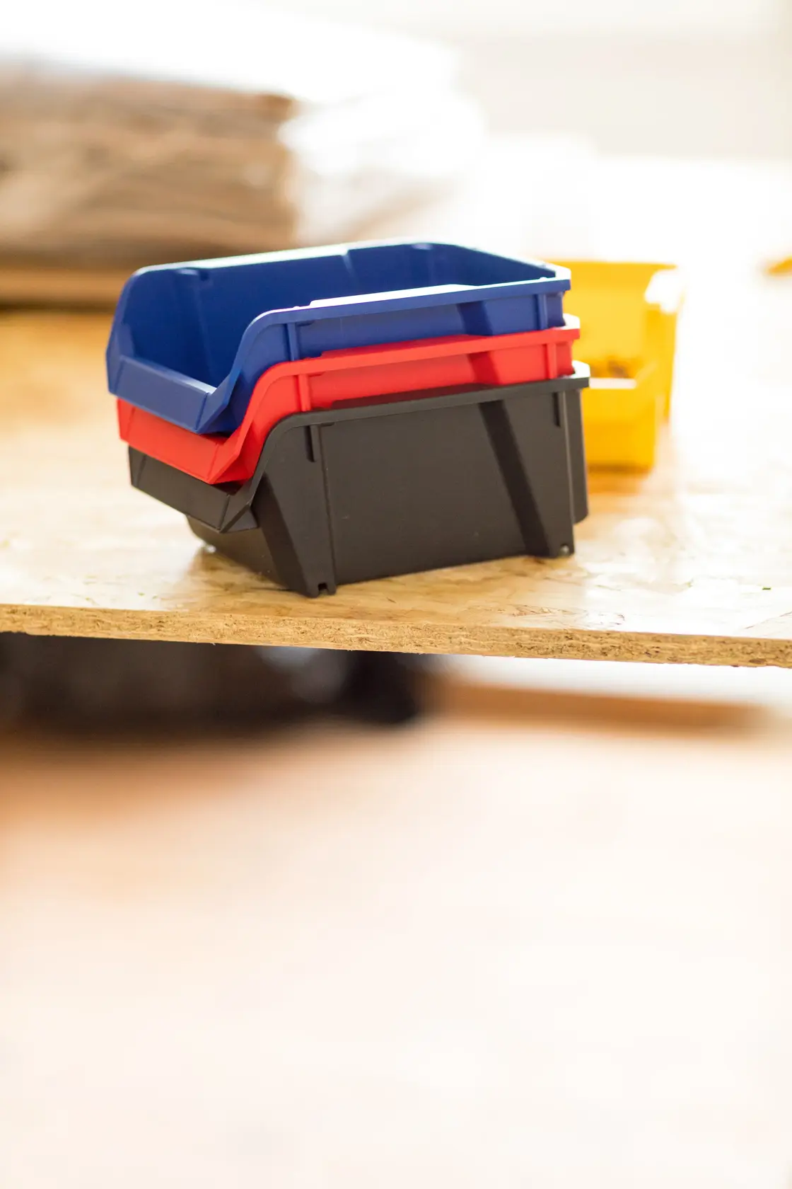 STANLEY STST82737-1 contenitori impilabili in plastica nero, rosso, blu, vista laterale su superficie di legno.