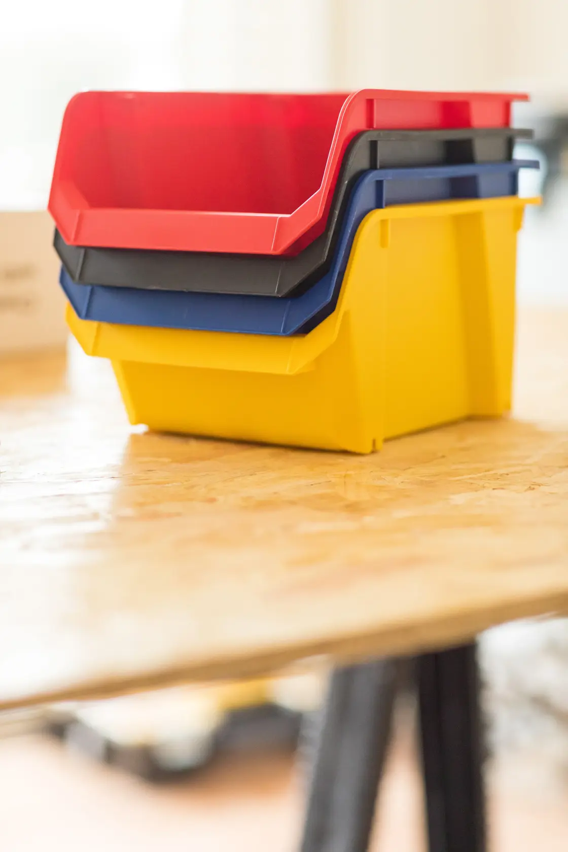 STANLEY STST82739-1 contenitori impilabili in plastica rosso, nero, blu e giallo su tavolo di legno, vista laterale.