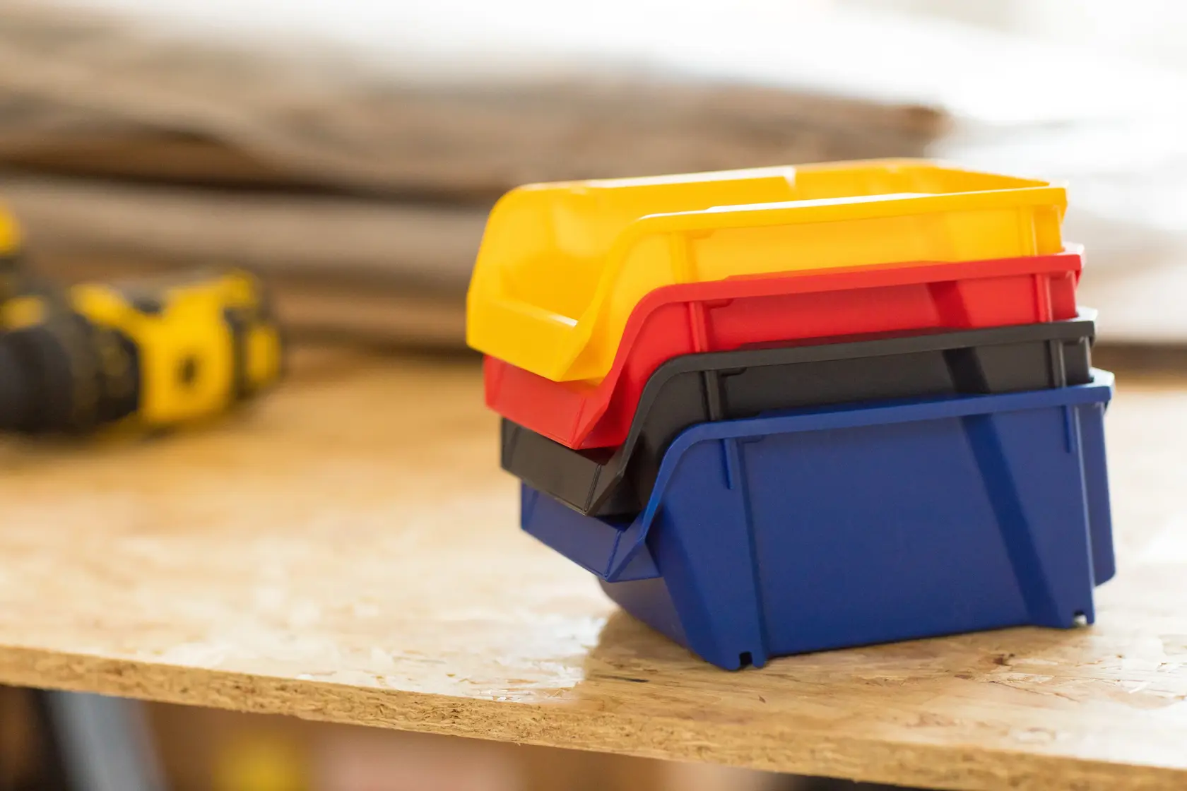 STANLEY STST82740-1 contenitori impilabili in plastica giallo, rosso, nero e blu su banco da lavoro, vista laterale.