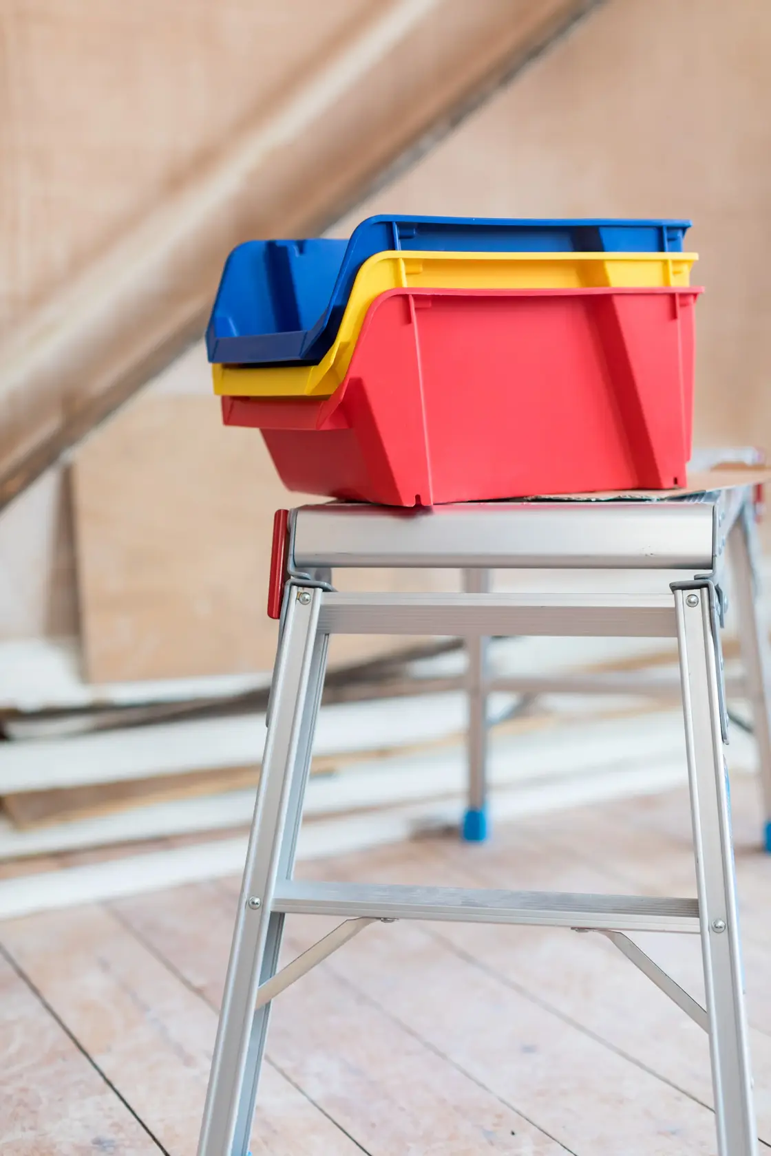 STANLEY STST82742-1 contenitori impilabili in plastica rosso, giallo e blu su banco da lavoro in metallo.