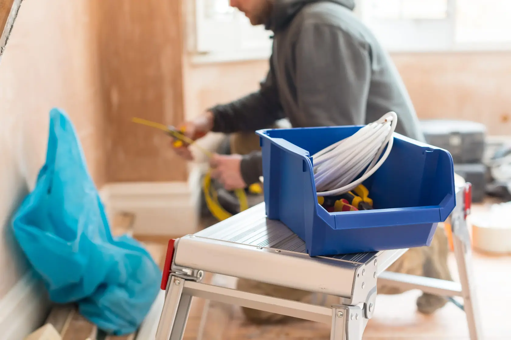 STANLEY STST82743-1 contenitore blu per cavi e attrezzi su una scala in un'area di lavoro.