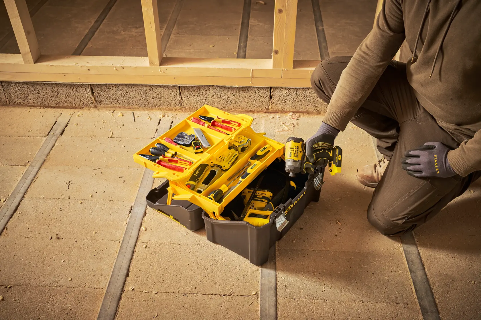 Cassetta attrezzi STANLEY STST83397-1 aperta con strumenti assortiti e trapano in cantiere.