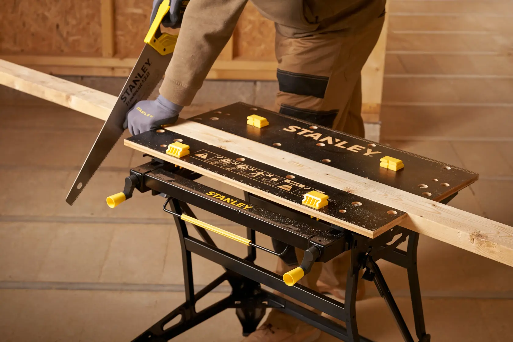 Stanley STST83800-1 banco da lavoro con asse di legno, sega a mano e persona che sega in laboratorio. Prodotto fotografia.