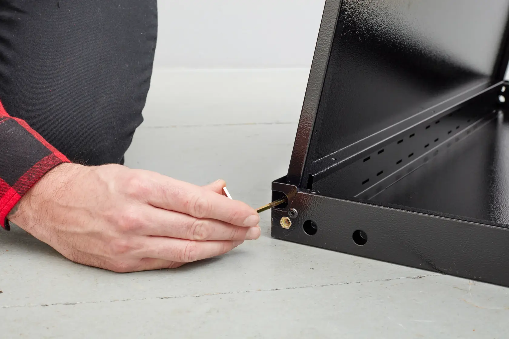 STANLEY STST97595-1 persona assembla telaio in metallo nero con chiave esagonale, primo piano su mano e angolo.