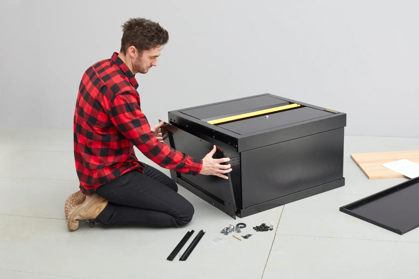 Assemblaggio del bauletto portautensili nero STANLEY STST97595-1 in corso con ferramenta e pannelli a terra.