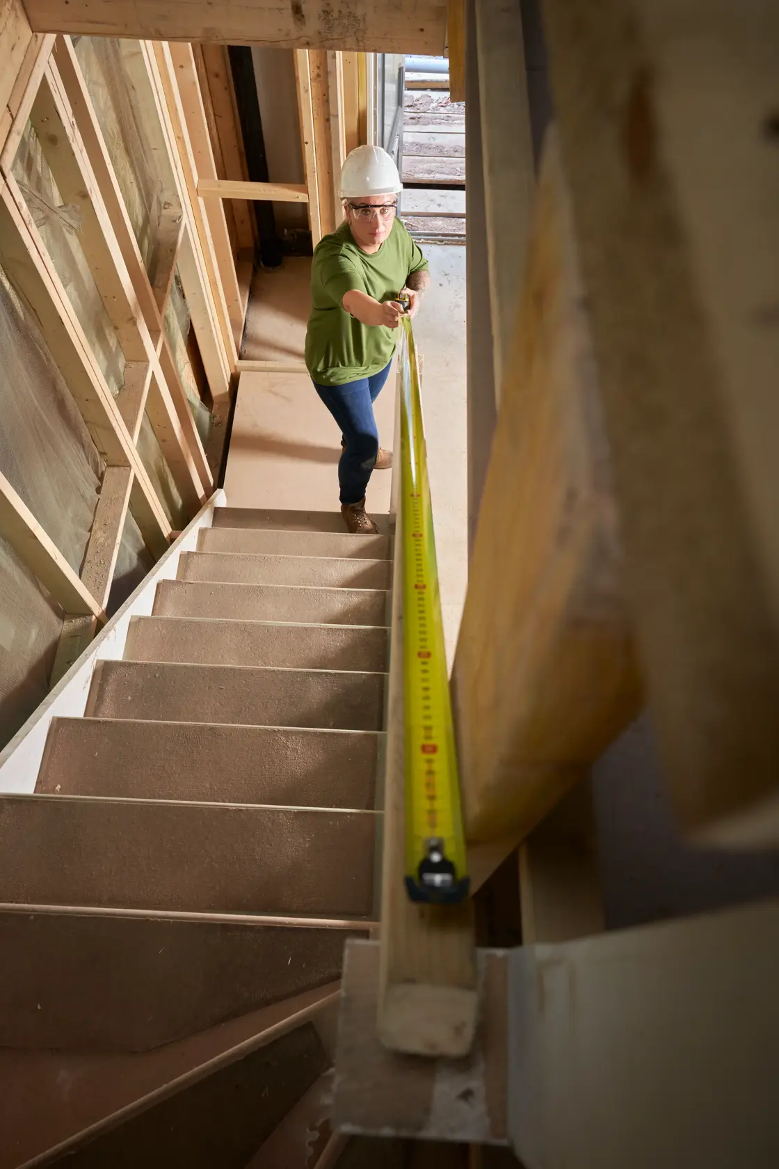 STANLEY XTHT0-33501 metro a nastro usato su scala da persona con dispositivi di sicurezza, contesto di costruzione.